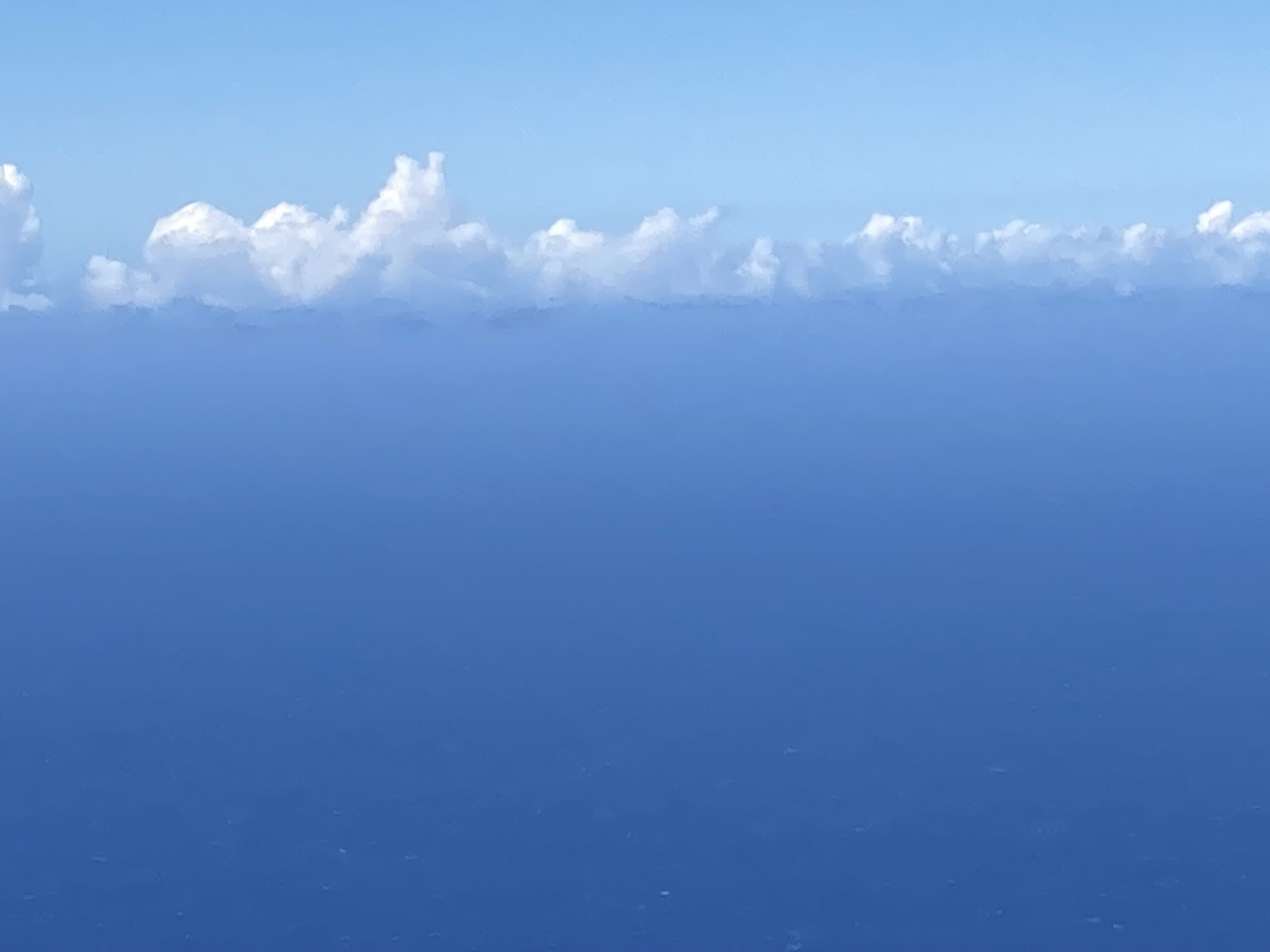 Blue sky with puffy white clouds over Pacific Ocean.